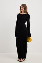 Long black knit dress with balloon sleeves paired with a stylish yellow handbag accessory