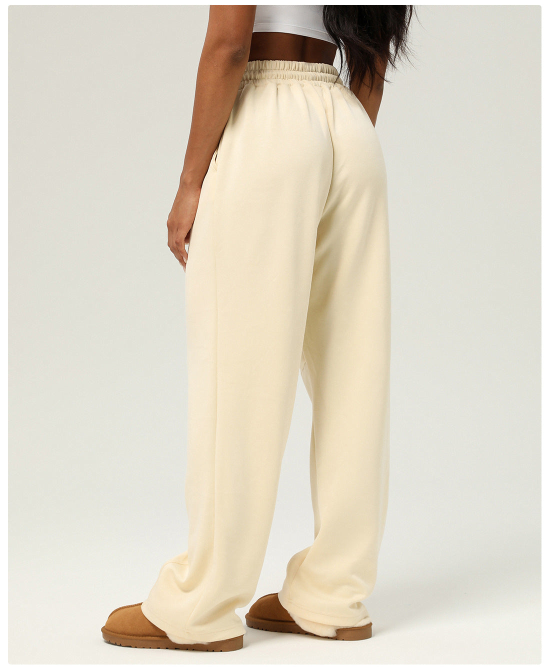 Cream-colored wide-leg sweatpants paired with brown slippers for stylish casual fitness wear