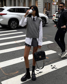 Preppy street style fashion featuring a Loose Knit Vest Sweater, pleated skirt, and boots