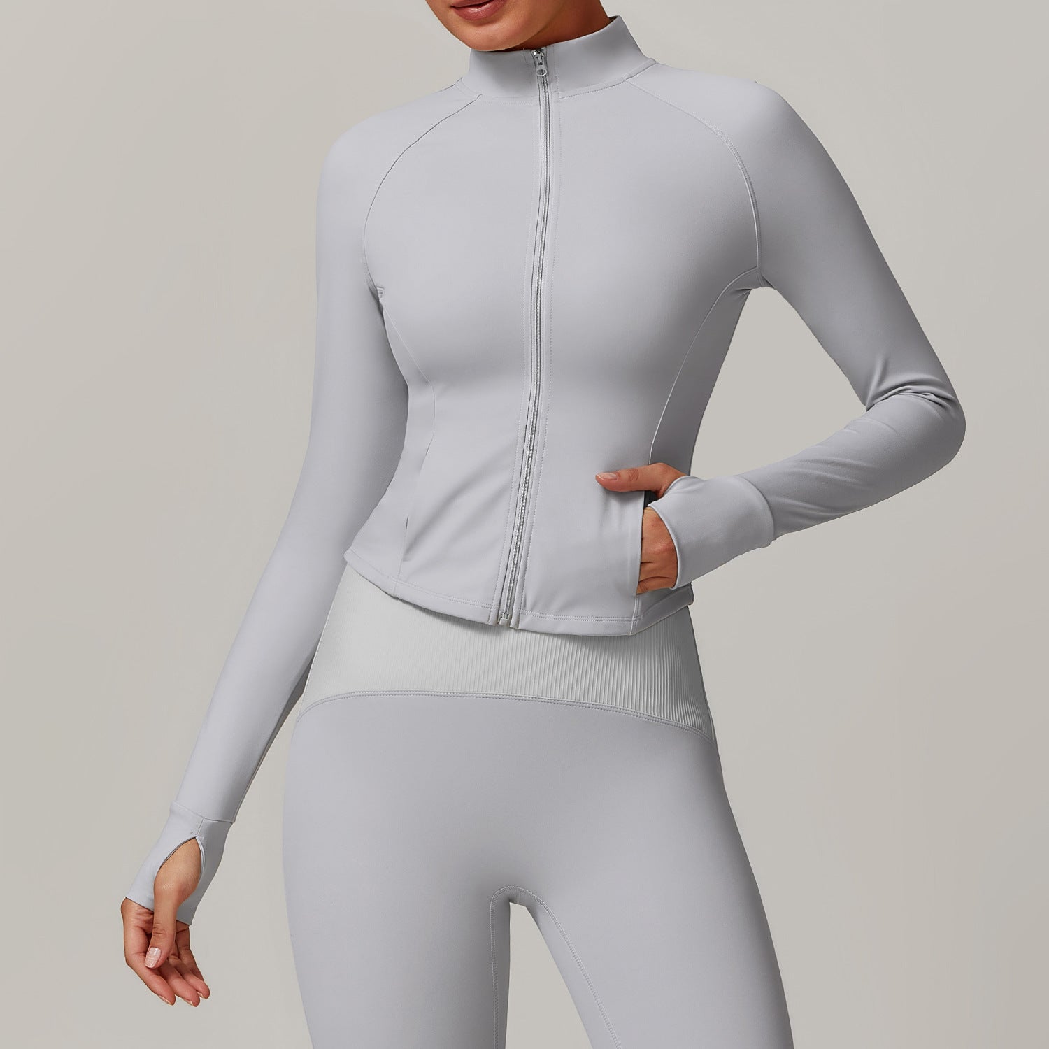 Light gray zip-up athletic jacket with mock neck and thumb holes for stylish yoga fashion