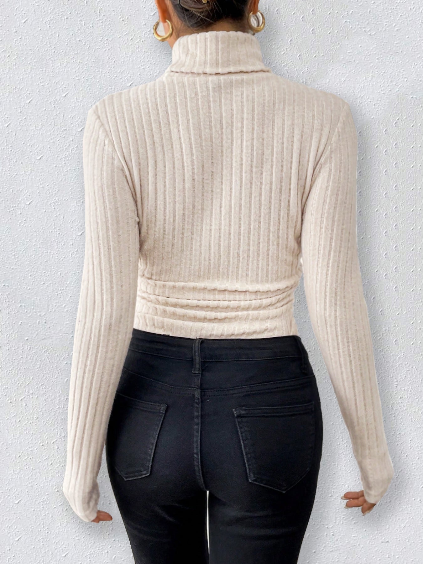 Cream-colored ribbed turtleneck sweater styled with dark jeans for elegant fashion versatility