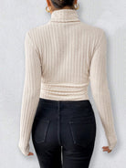 Cream-colored ribbed turtleneck sweater styled with dark jeans for elegant fashion versatility