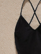 Black ribbed tank top with cross-back straps, perfect for a stylish swimwear look