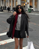 Stylish winter fashion featuring a gray sweater and burgundy scarf with black skirt and blazer