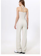 White halter-neck jumpsuit with wide-leg pants and sneakers for trendy fashion ملابس