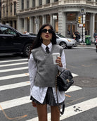 Preppy fashion look featuring gray vest sweater, pleated skirt, and sunglasses with coffee