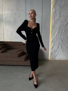 Woman in a black long-sleeved dress showcasing modern fashion in ملابس selections