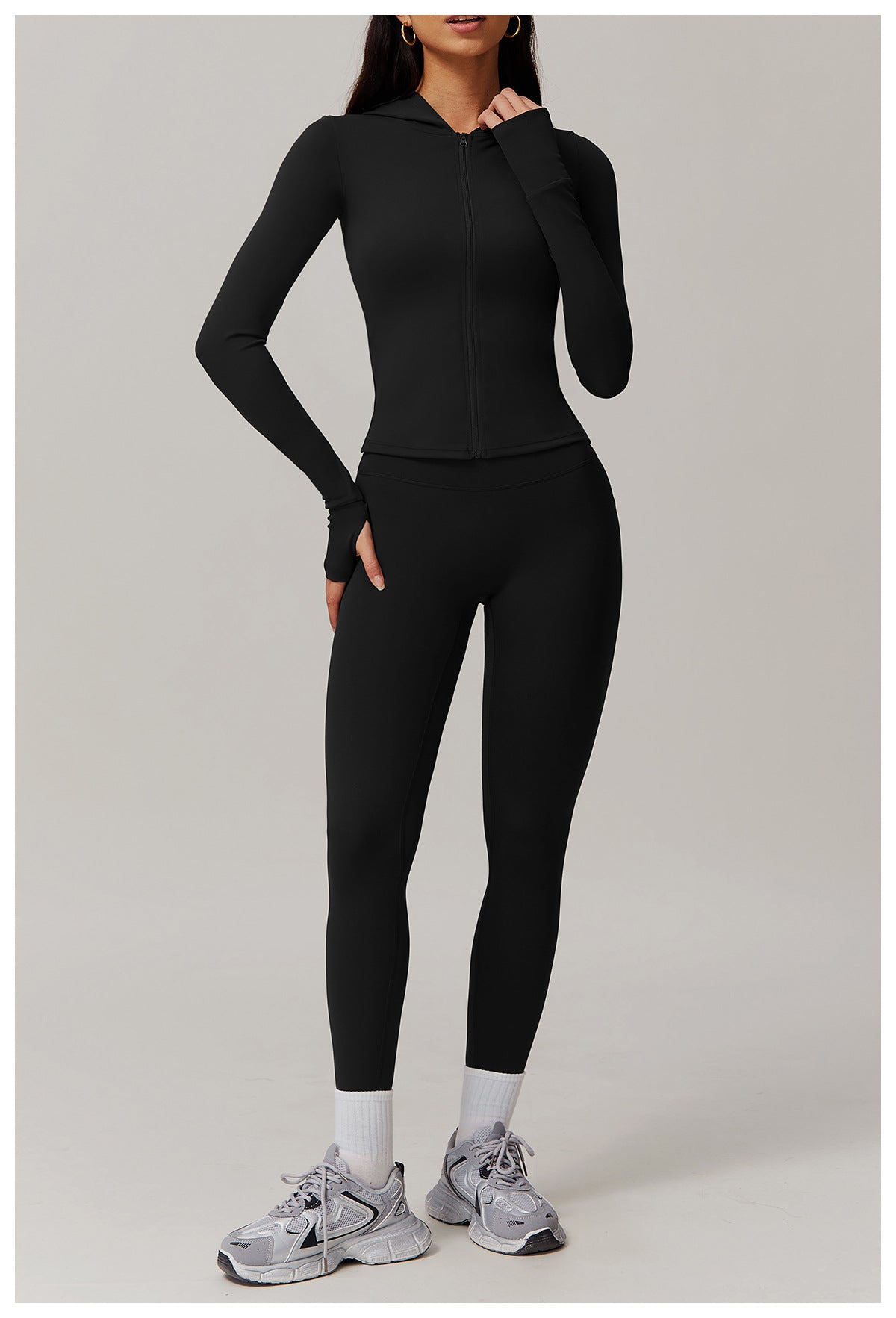 Black long-sleeved athletic jumpsuit styled with white socks and gray sneakers for langry fashion