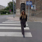 Someone in a stylish black and white striped jumpsuit with leather jacket on a crosswalk