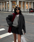 Fashionable winter outfit with dark blazer, pleated skirt, gray sweater, and burgundy scarf