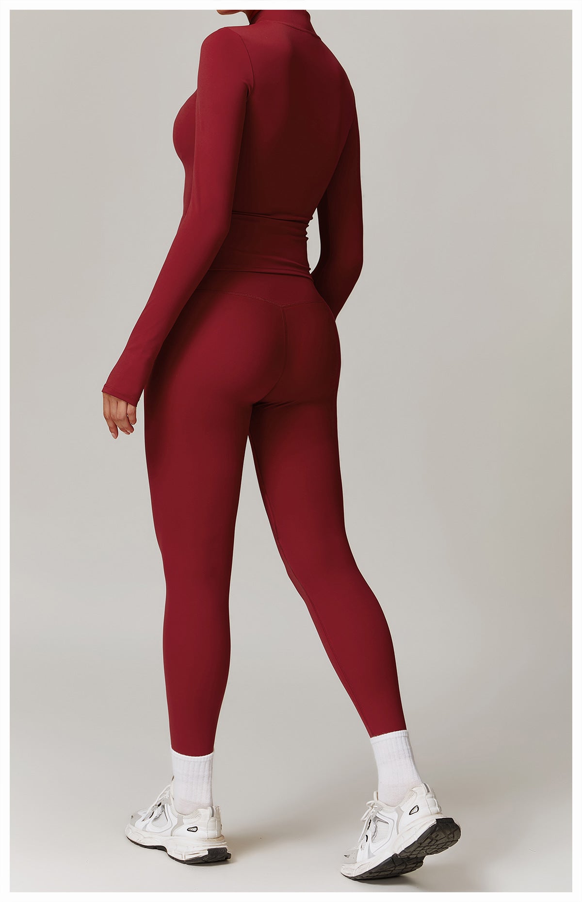 Deep red long-sleeved langry athletic jumpsuit with white socks and chunky sneakers