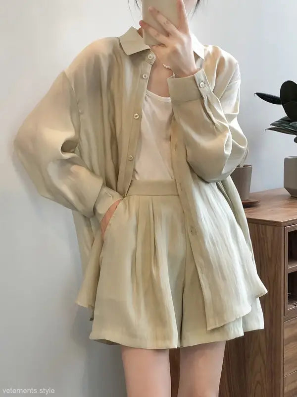 Cream-colored breathable sun protection outfit with a loose button-up shirt and pleated shorts