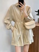 Beige button-up romper with long sleeves and cinched waist for breathable sun protection