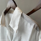 White linen shirt on a wooden hanger, complementing the Comfy Sunrise Cardigan set