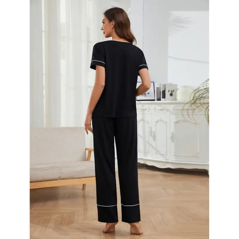 Black pajama set consisting of a short-sleeved top and long pants with white piping trim.