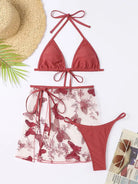 Three-piece red bikini set with a matching sheer floral skirt.