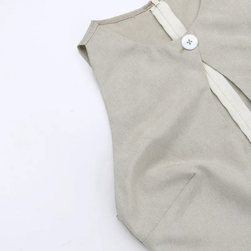 Sleeveless beige garment with a white button closure at the shoulder.