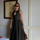 Woman wearing a long black sleeveless dress and sunglasses.