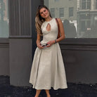 Woman wearing an elegant cream-colored midi dress with a keyhole neckline.