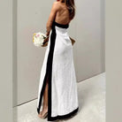 Elegant white strapless gown with black trim and a side slit, worn by a woman holding a bouquet.