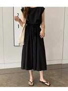 Black sleeveless midi dress with a gathered waist and flowing skirt.