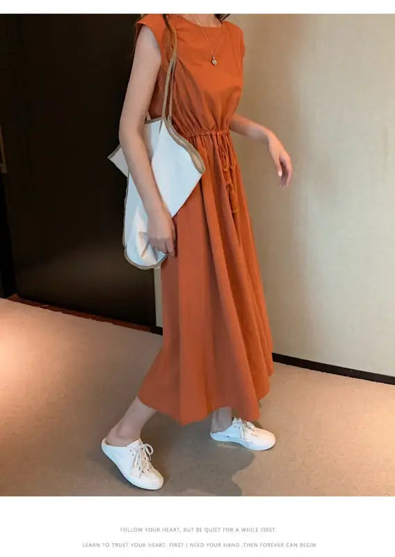 Orange sleeveless maxi dress with a cinched waist.