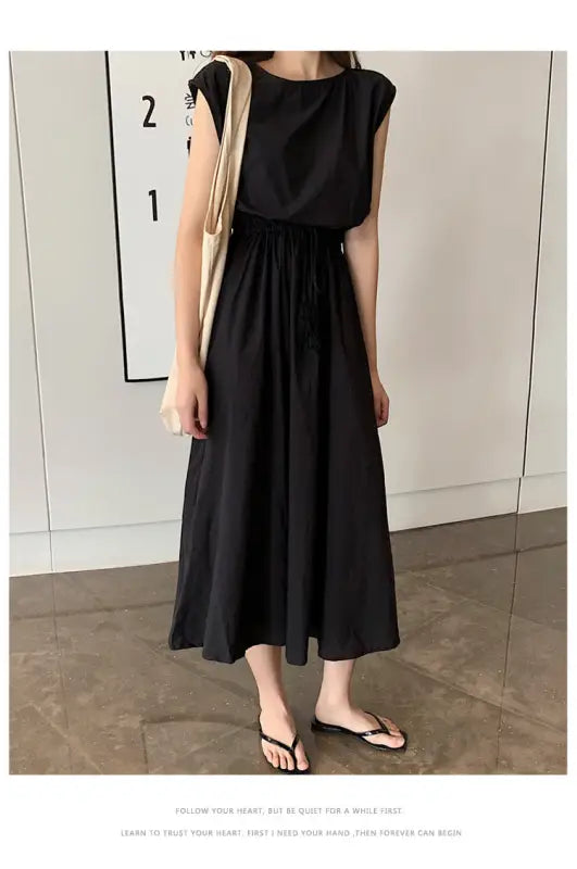 Black sleeveless maxi dress with a gathered waist and flowy skirt.