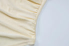 Cream-colored fabric with gathered or ruched texture along an edge.