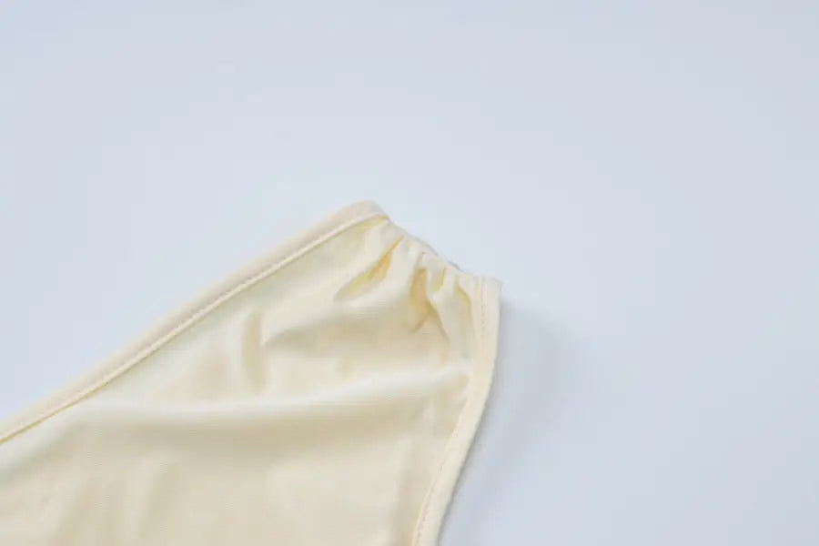 Cream-colored fabric or garment edge with gathered elastic or stitching.