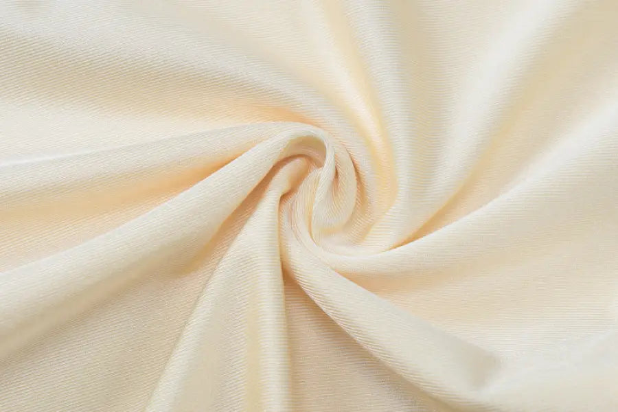 Swirled cream-colored fabric with soft folds and a silky texture.