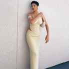 Woman wearing a form-fitting cream-colored evening gown with an asymmetrical neckline.