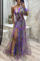 Flowing purple and yellow one-shoulder gown with a high slit and floral waist detail.