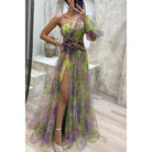 Flowing one-shoulder gown in green and purple with a high slit and floral accent at the waist.