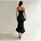 Black form-fitting evening dress with spaghetti straps and a ruffled mermaid-style hem.