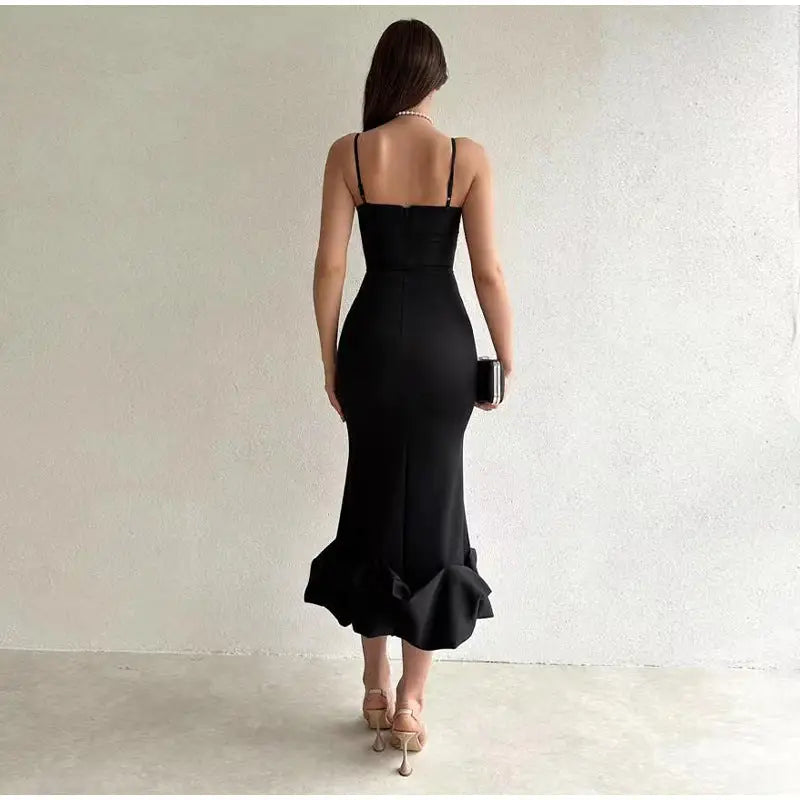 Black form-fitting evening dress with spaghetti straps and a ruffled mermaid-style hem.