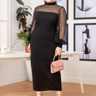 Black long dress with sheer sleeves and a high neckline, paired with a small pink handbag.