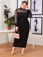 Elegant black long-sleeved dress with sheer upper bodice and sleeves, paired with a pink handbag and nude sandals.