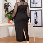 Black floor-length dress with sheer long sleeves and a high slit.