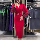 Vibrant red dress with puffed sleeves, a plunging neckline, and a bejeweled belt.