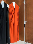 Bright orange sleeveless dress with a plunging neckline hanging on a display.