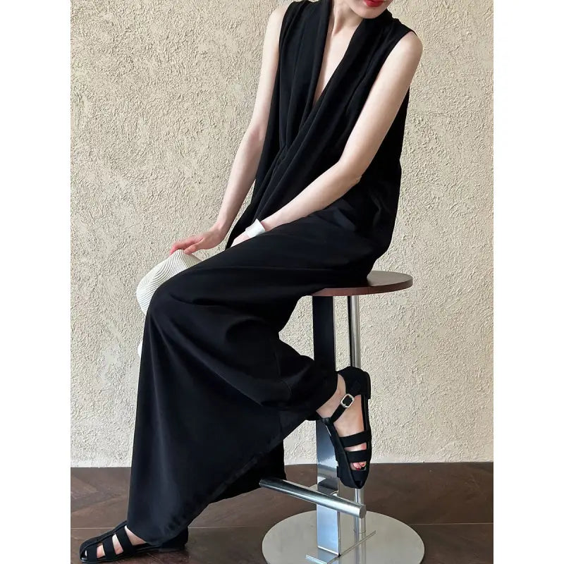 Sleek black jumpsuit with wide-leg pants and a plunging neckline, paired with strappy sandals.