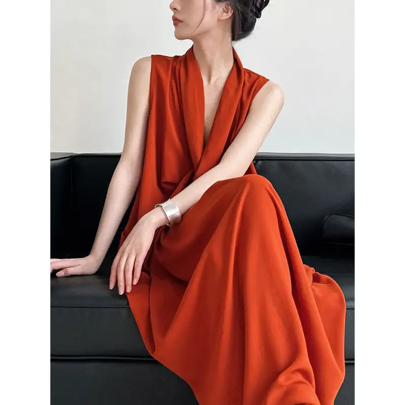 Sleeveless orange dress with a plunging neckline worn by a woman sitting on a dark couch.