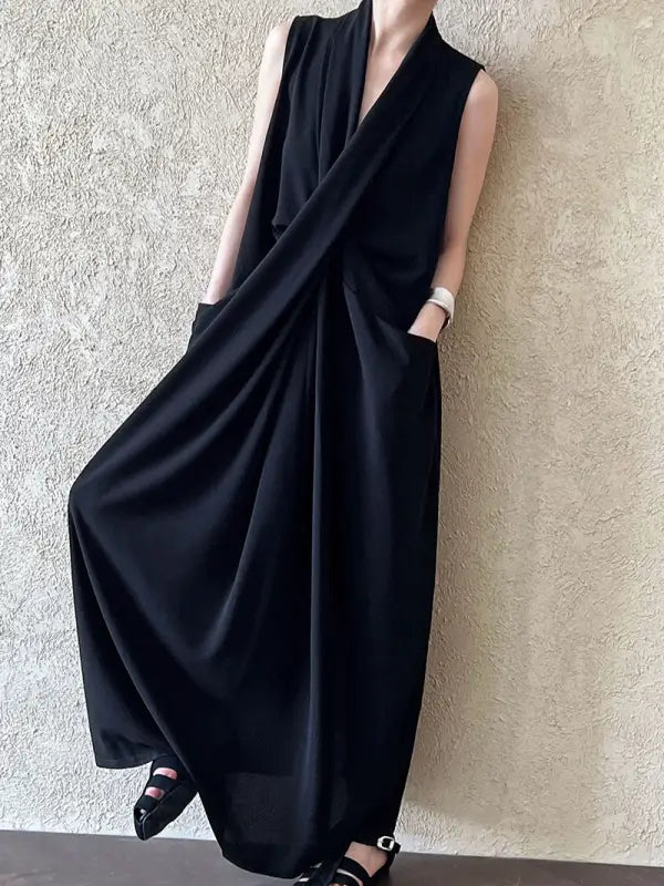 Sleeveless black maxi dress with a draped, wrap-style design and pockets.