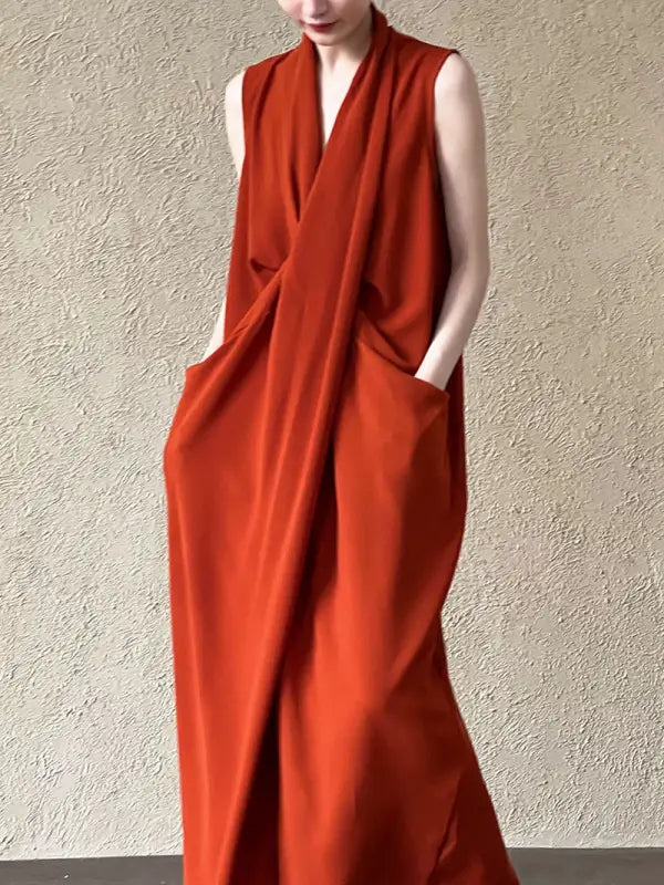 Sleeveless rust-colored maxi dress with a draped, wrap-style design and pockets.