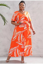 Vibrant orange maxi dress with white leaf print and short sleeves.