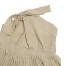 Beige one-shoulder dress or top with a tied bow and pleated skirt portion.