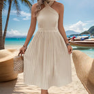 White halter-neck pleated sundress with a fitted waist.