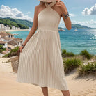 Elegant cream-colored halter neck dress with a pleated skirt.