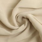 Cream-colored fabric with a soft, textured appearance twisted into a spiral fold.