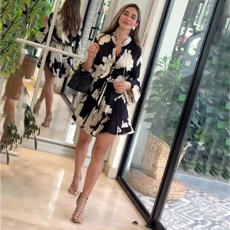 Woman wearing a black and white floral print dress with strappy sandals.